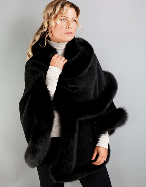 A blonde woman with green eyes wearing medium length black cape over an ivory turtleneck. In this photo the cape is worn with one side wrapped across the chest and over the opposite shoulder