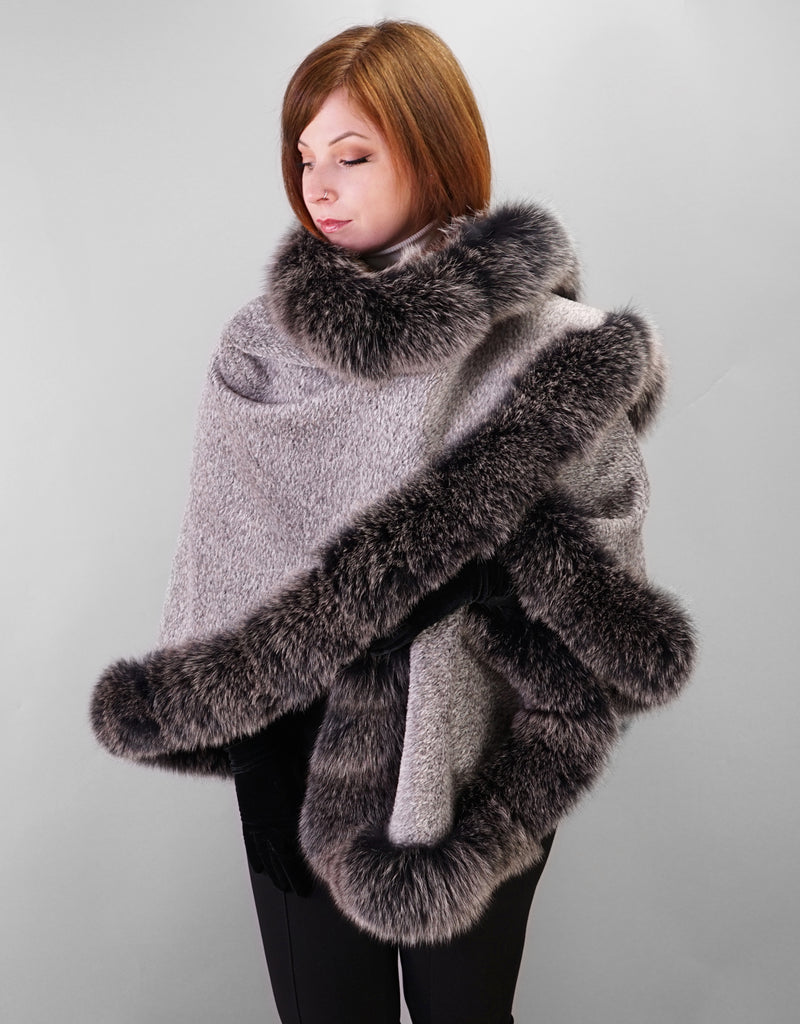 A red haired woman is wearing a medium length silver cape with Black Snow Fox trim and black leather gloves. In this photo the cape is worn with one side wrapped across the chest and over the opposite shoulder
