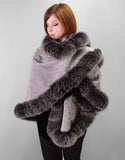 A red haired woman is wearing a medium length silver cape with Black Snow Fox trim and black leather gloves. In this photo the cape is worn with one side wrapped across the chest and over the opposite shoulder