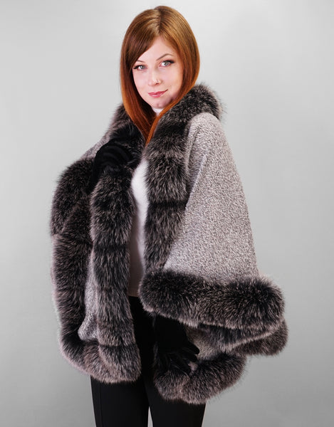 A red haired woman wearing medium length silver textured cape with  Fox trim black with white tips and black leather gloves