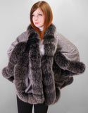 Front view: A red haired woman is wearing a medium length silver cape with black with white tips Fox trim and black leather gloves